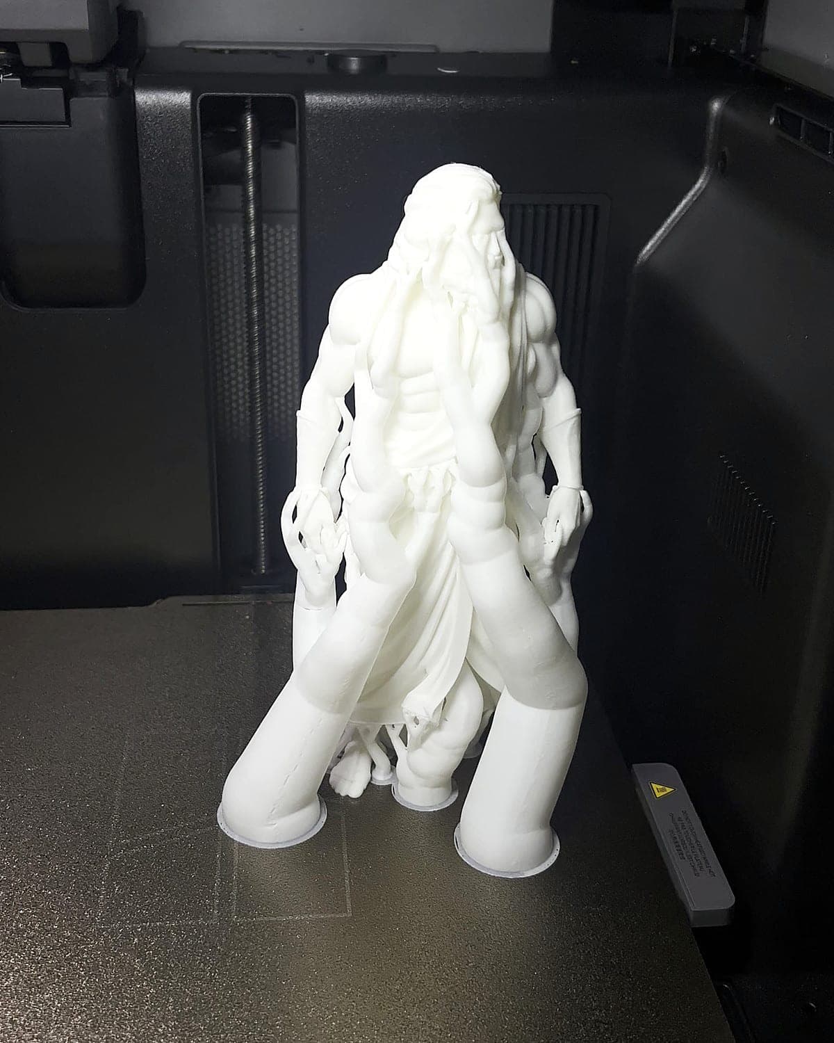 The Zeus figurine straight off the printer, still standing in its white tree supports on the print bed