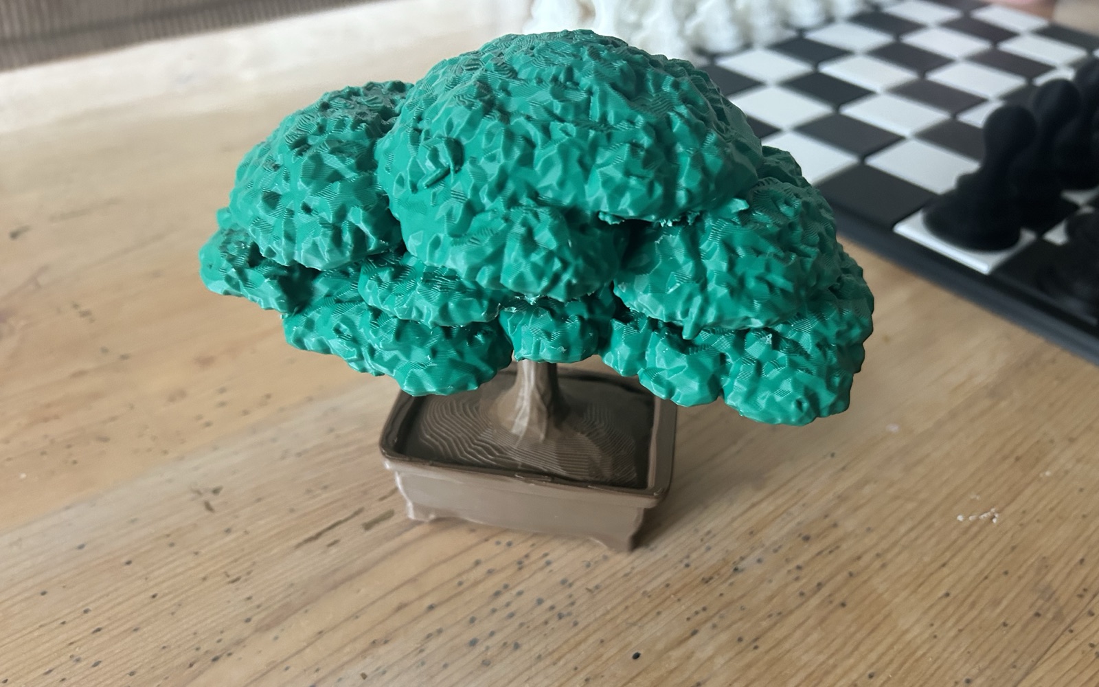 A multicolour 3D-printed bonsai keepsake - green canopy, brown pot - on a workshop bench